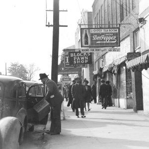 People walking down sidewalk under various advertising signs