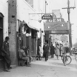 African American men and women walking down sidewalk under signs