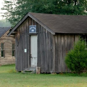 Single story wooden building with sign saying "Steele School 1868"