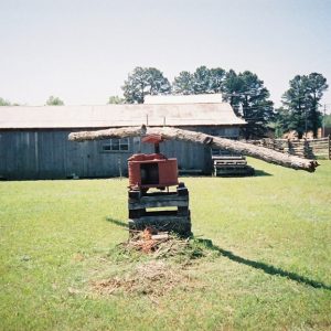 Long log attached to machine with building behind