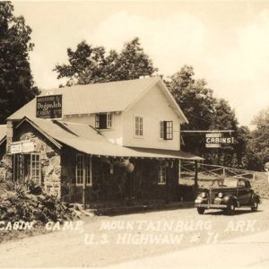 Multistory stone and wood building with signs saying "Dogpatch Cabins"