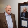 White man standing next to framed portrait of himself