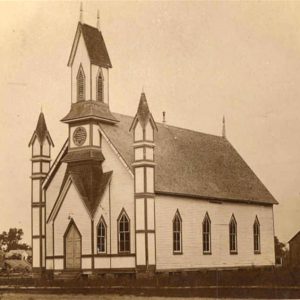 Multistory wooden church building with two small towers and one tall one