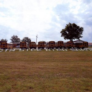 letters on ground "South Side High School" on grass by row of school buses