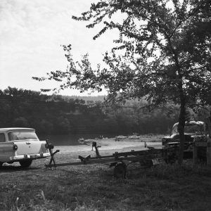 Cars and boat trailers parked near river