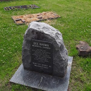 Picnic tables beneath covering in front of raised stone with plaque on it