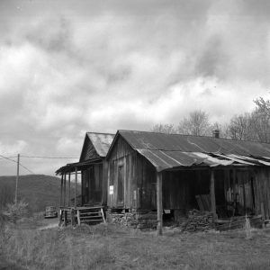 Single story abandoned wooden buildings with old car in the background