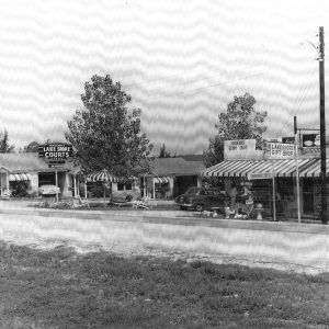 Row of single story buildings along street with cars