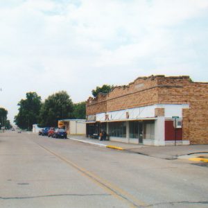 Street running between rows of buildings with cars parked at street side