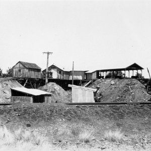 Wooden and metal buildings on mound of dirt and below it