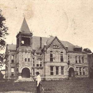 Multistory brick building with tower and arched entrances