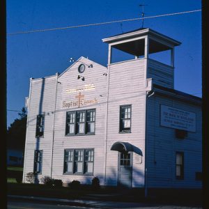 Multistory white wooden church building with a short tower