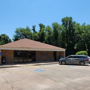 Single story red brick building with parking lot and cars