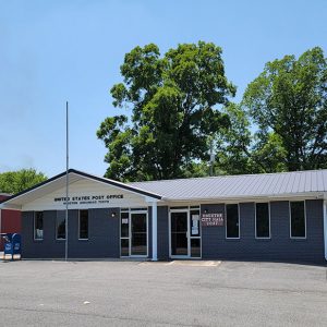 Single story gray brick building with light gray roof amid parking lot