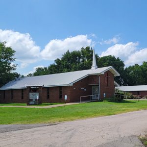 Single story red brick church building with small steeple