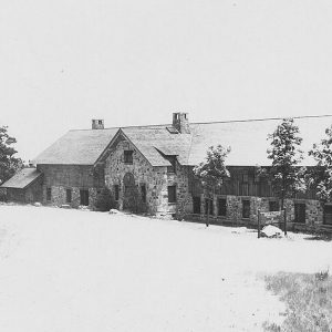 Multistory rock and wooden building with car parked at one end