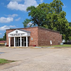 Single story red brick building with entrance with covering and four white columns