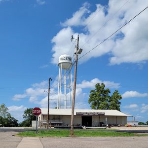 intersection and a hardware store with a water tower in the background with the word "Magazine" on it