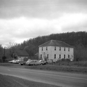 Two wooden buildings with cars parked out front and at the side