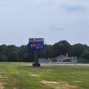 Single story red brick school buildings with sign "Two Rivers School District" amid expanse of grass