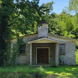 Abandoned wooden church building with bell tower amid trees