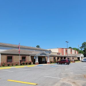 Row of connected multistory buildings with parking lot and cars