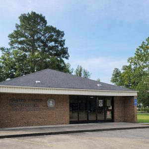 Single story tan brick building with American flag on pole