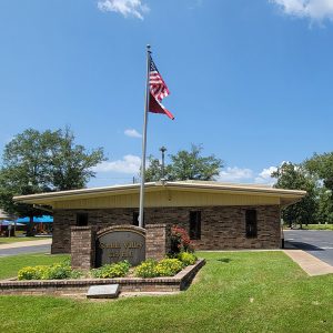 Single story parti-colored brick building next to park pavilion