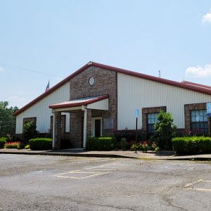 Multistory brick and cream-colored building with red trim and parking lot