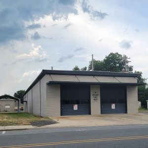 Single story tan brick building with two garage doors