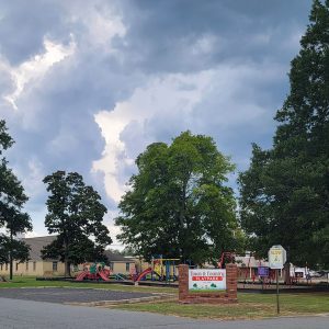 Playground with children's playground equipment and some picnic tables and parking spaces