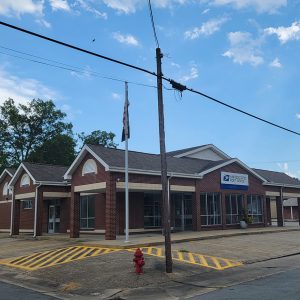 Single story red brick building with multiple entrances and parking spaces