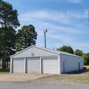 Single story white metal building with three garage doors