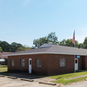 Single story red brick building with American flag on pole "Kensett Masonic Lodge" and parking lot