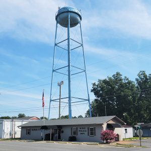 Single story gray block building with blue water tower behind