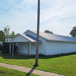 Single story white concrete block building lacking windows