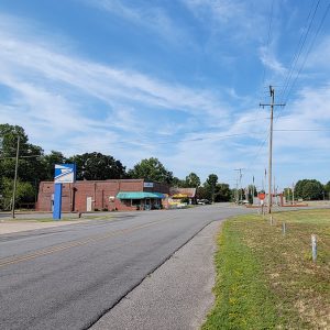 Road next to railroad tracks going into a small town with a few businesses