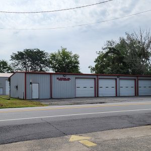 gray metal building with four garage doors and one entrance door by road