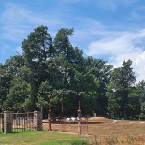 Cemetery with trees and gravestones and a fence with brick columns