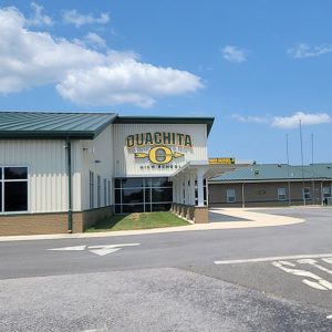 Brick and metal building with "Ouachita High School" on the front with a yellow "O" with an arrow going through it