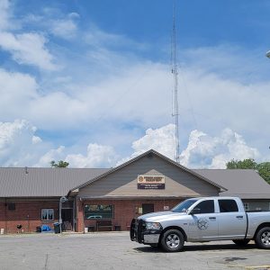 Single story red brick building with police pickup truck parked in front