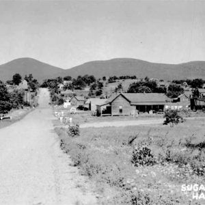 Road running through small town with mountains in the background