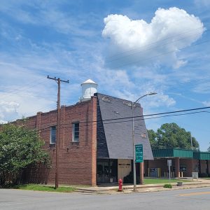 Multistory red brick building with black extended roof on front