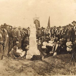 Large group of white men in hats surrounding a smaller group of men