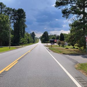 Small town street scene with road running past a gas station and trees