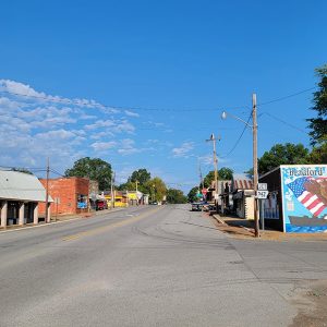 Small town street scene with rows of storefront buildings and colorful mural