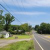 Country road crossing railroad tracks with houses and trees on the side