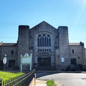 Multistory stone church building with stained-glass window in front