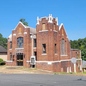 Multistory red brick church building with stained glass window in front