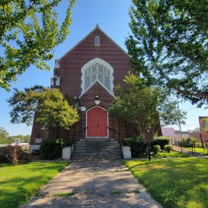 Multistory red brick church building with steps leading up to red doors